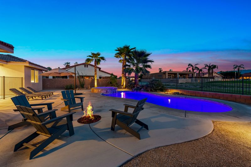 Backyard fire pit seating beside the pool at dusk at Palms Place