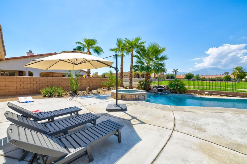 Covered patio and pool loungers at Palms Place vacation rental