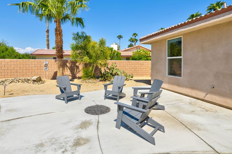 Fire pit with Adirondack chairs beside the pool at Palms Place